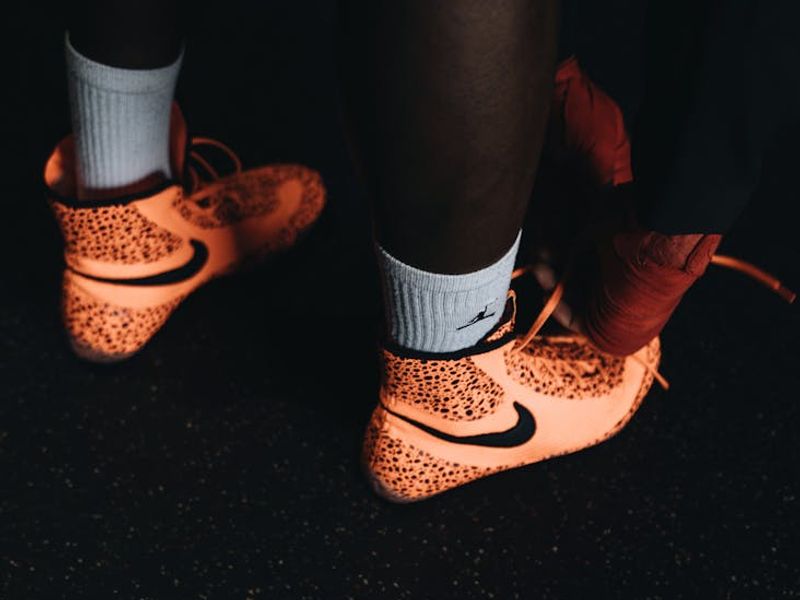 Close up of sports shoes and a stopwatch on a dark floor